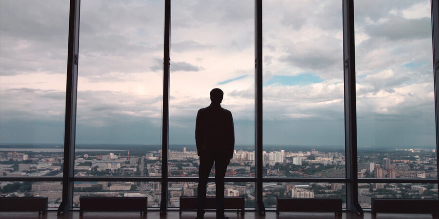 Rear view of man in formal suites who stand in front of panoramic window with city view. a man stands in front of big panoramic wiindow view from back HD